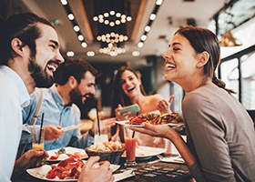 Friends eating meal, enjoying lifestyle benefits of dental implants