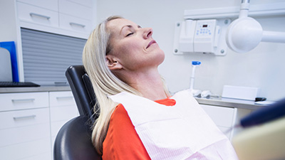 Woman in dental chair with eyes closed