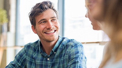 man smiling while talking to person 
