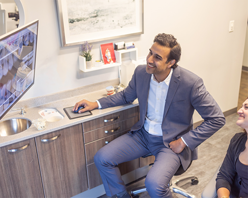 Doctor Kumar looking at a computer screen with a patient
