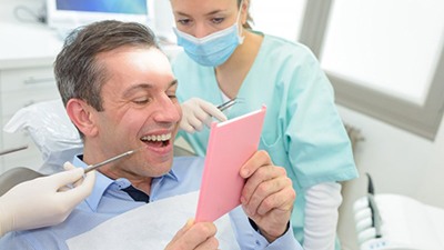 a patient checking his new dental bridge with a mirror