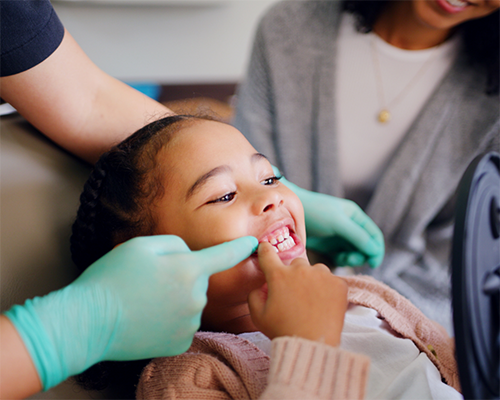 Young girl looking at her smile in the mirror at the dentist