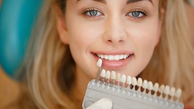 Woman's smile compared with tooth color chart