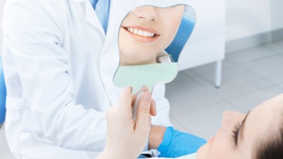 Dental patient admiring her teeth in mirror