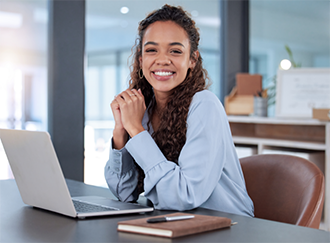 Woman in business attire at a table with a laptop