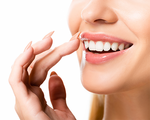 Close-up of a woman gesturing to her flawless smile