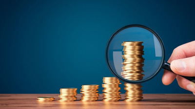 Magnifying glass examining increasingly larger stacks of coins