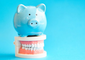 Piggy bank sitting on top of a dental model