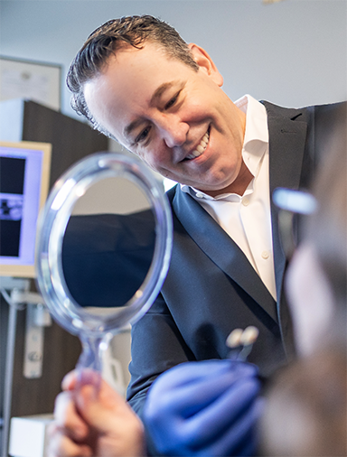 Doctor Roy showing a patient their new smile in a mirror
