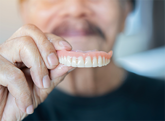Man holding his denture