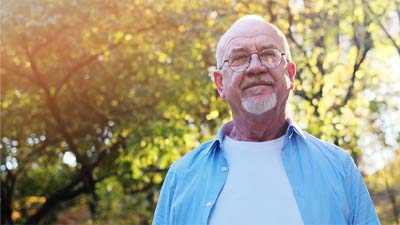 older man standing outside looking at camera