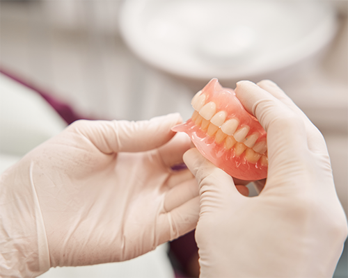 Gloved hands holding a set of dentures