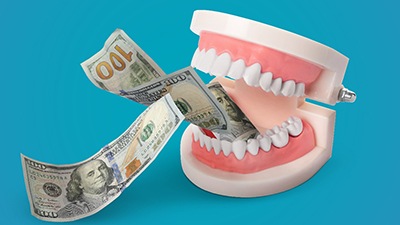 Model dentures biting a couple hundred-dollar bills