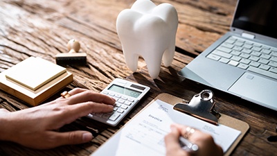 A dental insurance form next to a model tooth and laptop