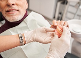 Close-up of dentist showing full dentures to patient
