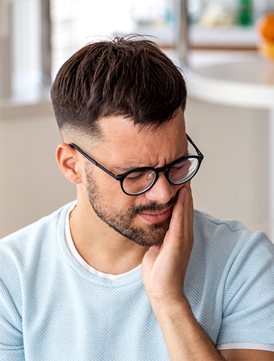 Young man holding his cheek in pain