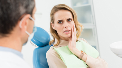 A young woman holding her cheek at the dentist office