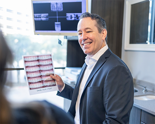 Doctor Roy holding photos of teeth