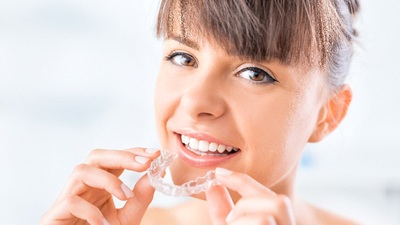 Woman holding Invisalign clear aligner