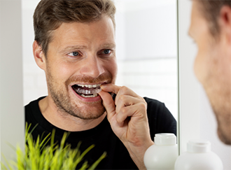 Man placing Invisalign over his teeth