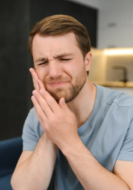 Young man holding his cheek in pain