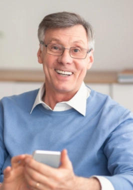 Older man in light blue sweater smiling