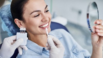 Patient using mirror to admire the results of her smile makeover