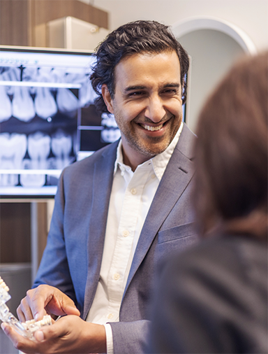 Doctor Kumar holding a denture while talking to a patient