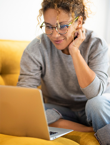 Woman using laptop on yellow couch