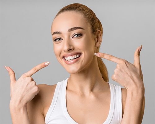 Blonde woman pointing to her smile