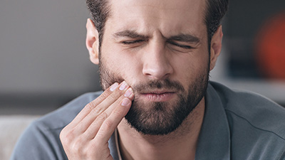 Man holding cheek in pain