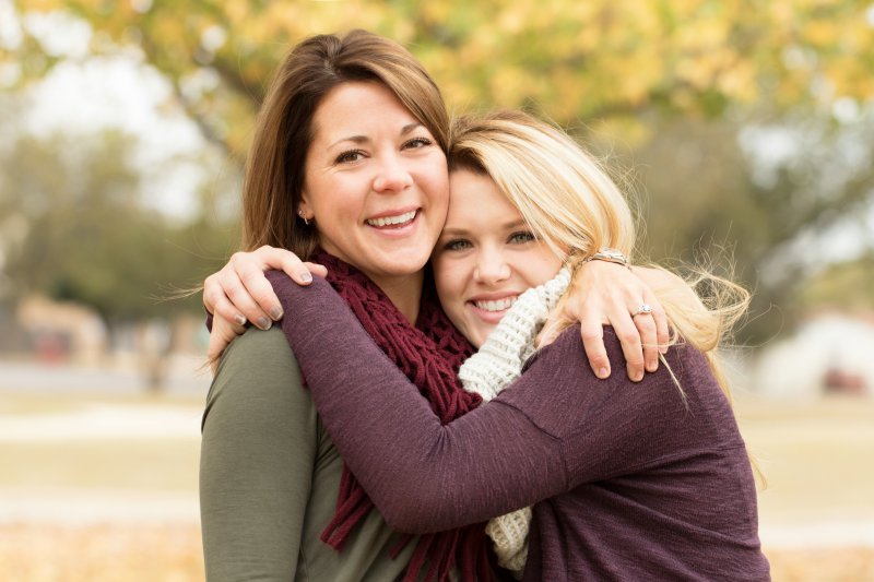 A mother and daughter hugging outside.