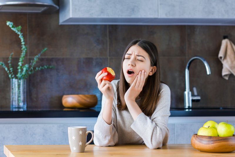 Woman eating an apple, nursing a toothache