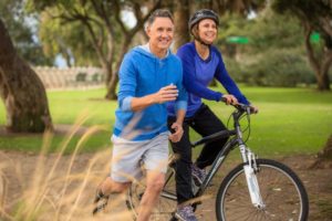 Man and woman without tooth pain smiling outside while working out