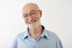 Older man with greying hair smiling with glasses