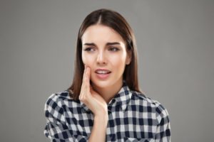 Woman with hand on her cheek due to dental pain