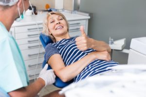 Woman smiling in dental chair giving thumps up