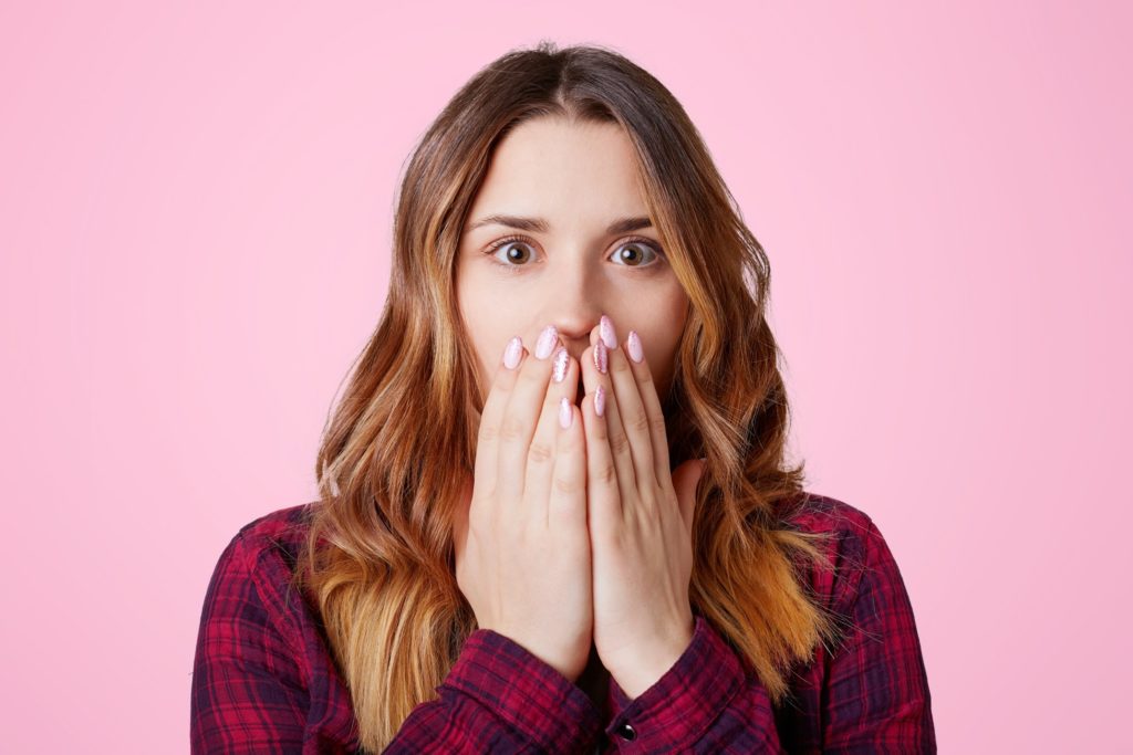 Woman in red flannel covering her mouth in shock