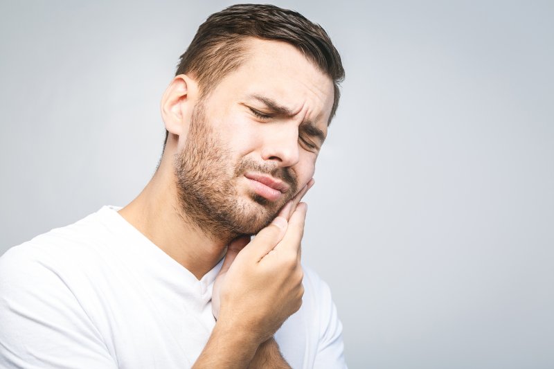 person experiencing with toothache holding cheek