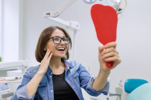 Patient admiring her smile after fixing cosmetic dental flaws