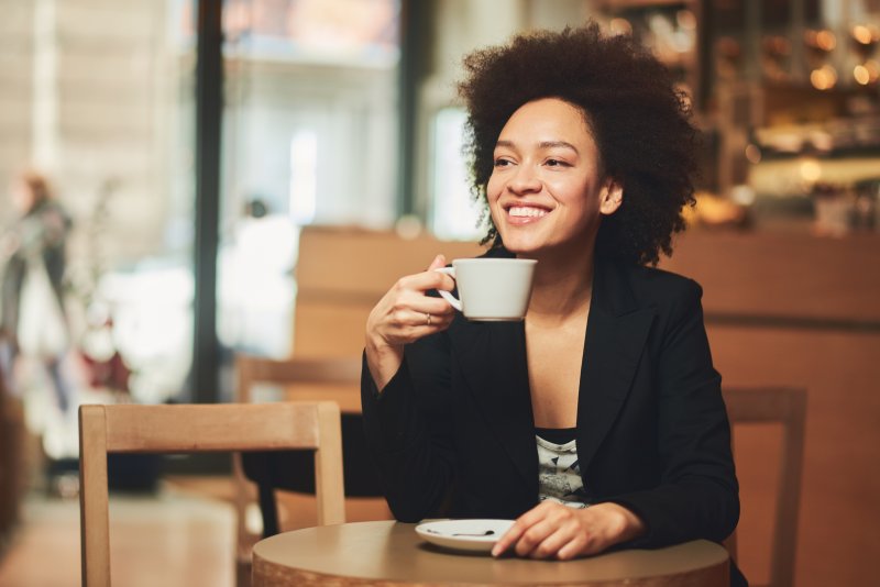 woman smiling while drinking cup of coffee