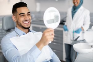 Happy patient using mirror to admire results of gum recontouring