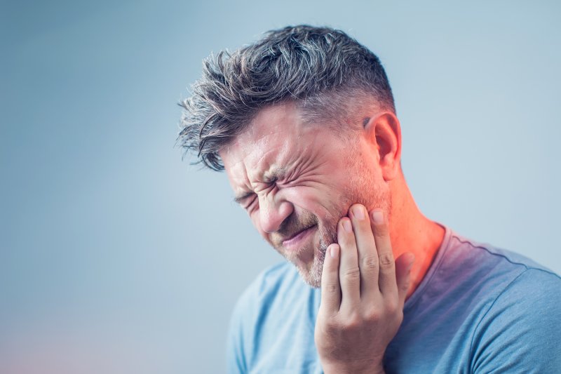 person holding their cheek in pain 